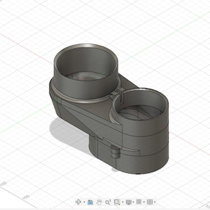 May include: A gray, 3D-modeled object with two cylindrical openings connected by a curved section. The object has a geometric design and appears to be made of a solid material. The background is a grid.