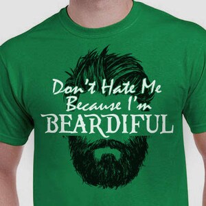 May include: Green t-shirt with a white graphic that says "Don't Hate Me Because I'm Beardiful" and a black and white illustration of a beard.