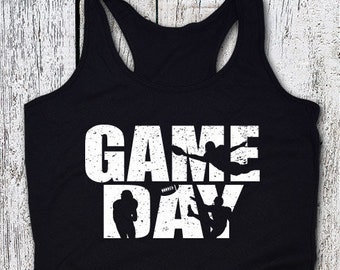 May include: Black tank top with the words "GAME DAY" in large white letters. Silhouettes of football players are incorporated into the text. The tank top has a racerback design.