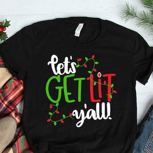 May include: Black t-shirt with a white graphic that says "Let's Get Lit Y'all!" with red and green Christmas lights around the text.