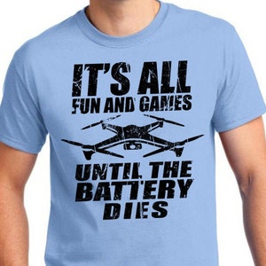 May include: A light blue t-shirt with a black graphic of a drone and the text "It's all fun and games until the battery dies."