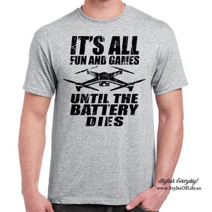 May include: Grey t-shirt with black text that reads "It's all fun and games until the battery dies." A black and white drone graphic is above the text.
