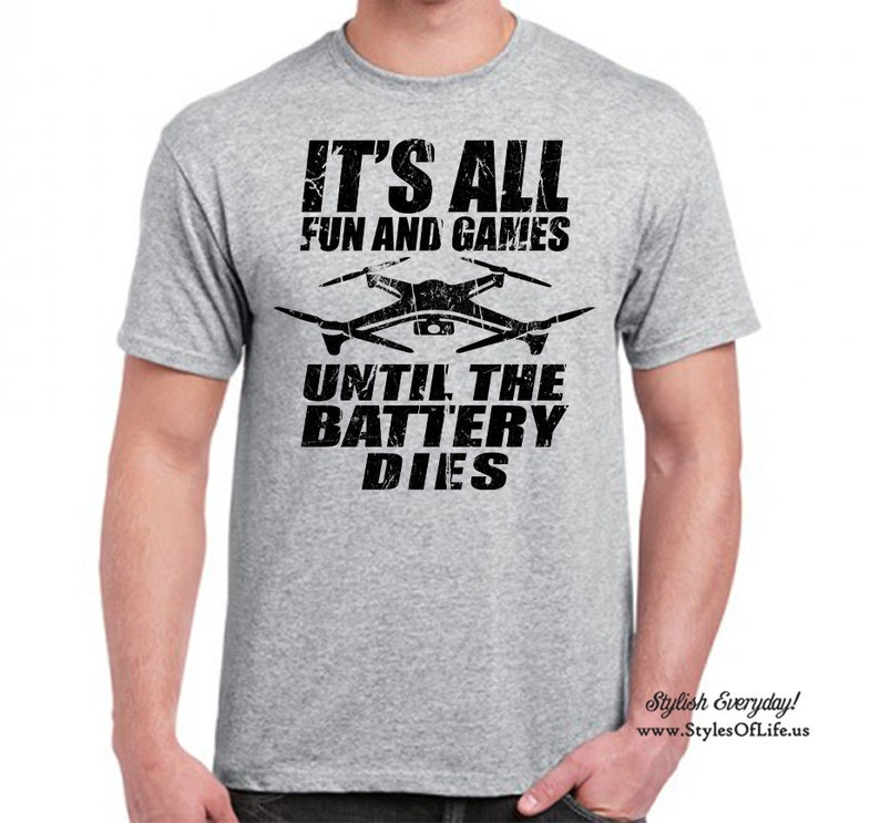 May include: Grey t-shirt with black text that reads "It's all fun and games until the battery dies." A black and white drone graphic is above the text.