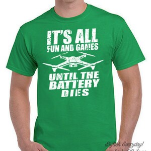 May include: Green t-shirt with a white graphic of a drone and the text "It's all fun and games until the battery dies."
