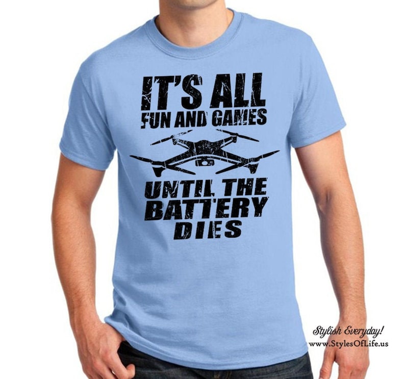 May include: A light blue t-shirt with a black graphic of a drone and the text "It's all fun and games until the battery dies."