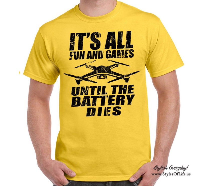 May include: Yellow t-shirt with black text that reads "It's all fun and games until the battery dies." A black silhouette of a drone is above the text.