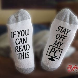 May include: A pair of white socks with black text. One sock says "If you can read this" and the other sock says "Stay off my PC".