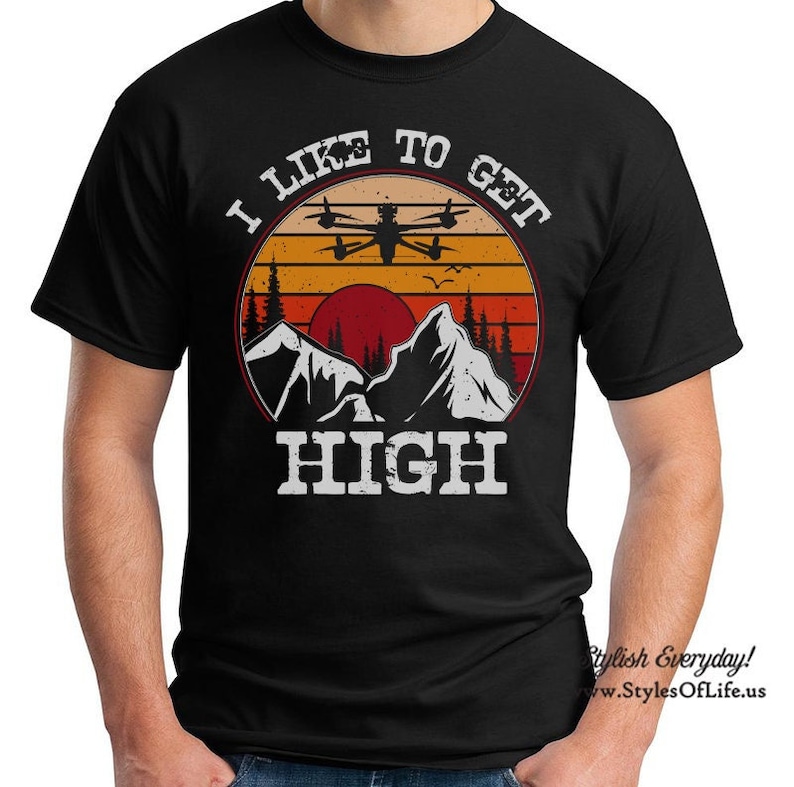 May include: Black t-shirt with a retro-style graphic of a drone flying over mountains with the text "I Like To Get High".