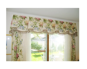 May include: A cream-colored valance with a floral pattern in shades of pink, green, and blue. The valance has a scalloped edge and a fringe trim.