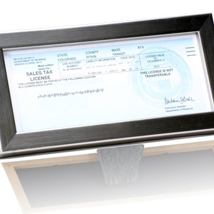 May include: A framed sales tax license for the state of Colorado, valid until December 31, 2023. The license is not transferable. The license is for Pitkin County and has a use account number of 57-0001-001. The license was issued on December 11, 2013.