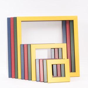 May include: A set of colorful picture frames in various sizes. The frames are made of wood and have a smooth finish. The frames are arranged in a staggered pattern, with the largest frame at the top and the smallest frame at the bottom.