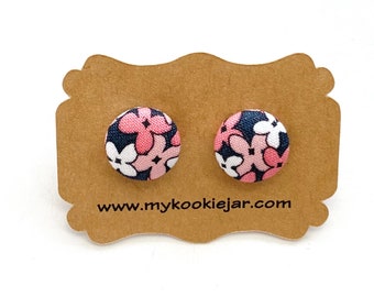 May include: A pair of stud earrings with a pink, white, and navy blue floral pattern. The earrings are displayed on a brown card with the website www.mycookiejar.com printed on it.