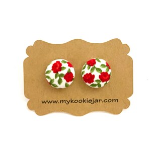 May include: A pair of red and green floral button earrings on a brown card with the text "www.mycookiejar.com".