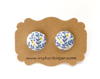 May include: A pair of stud earrings with a white background and a floral pattern in blue and yellow. The earrings are displayed on a brown card with the website address "www.mycookiejar.com".