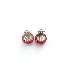 May include: A pair of red and white polka dot fabric covered clip-on earrings.