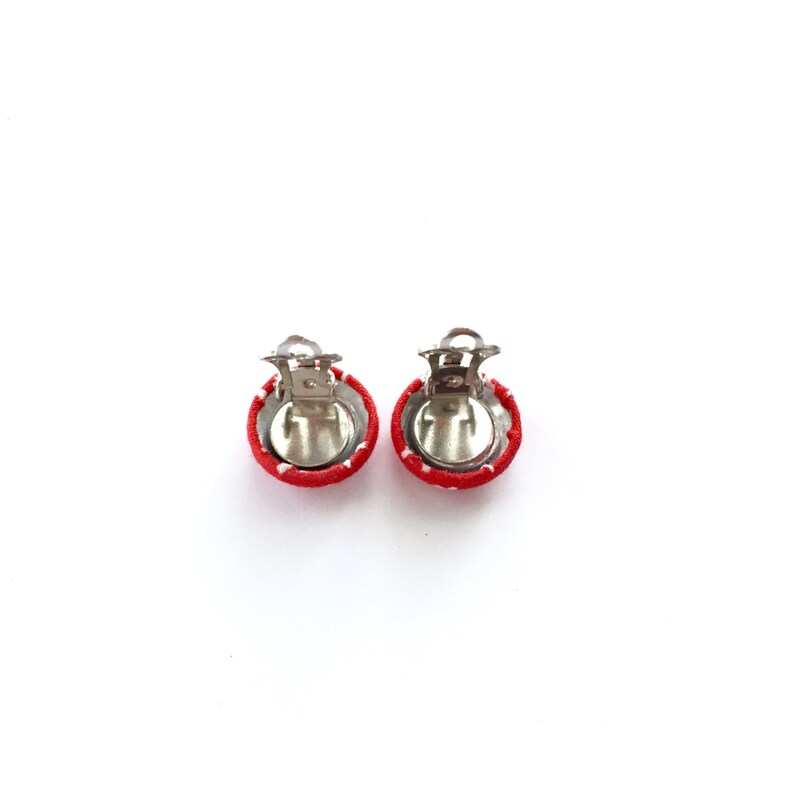 May include: A pair of red and white polka dot fabric covered clip-on earrings.