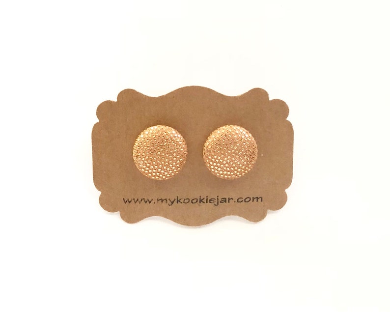 May include: A pair of gold stud earrings with a textured surface. The earrings are displayed on a brown card with the website address "www.mycookiejar.com".