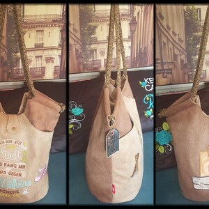 Könnte beinhalten: Eine braune Tragetasche mit Reißverschluss oben und braunem Lederboden. Die Tasche hat einen langen Riemen und ist mit Stickereien verziert. Die Tasche wird aus verschiedenen Blickwinkeln gezeigt, einschließlich der Innenauskleidung.