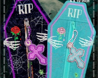 May include: Two coffin-shaped pencil cases, navy and teal, with embroidered details. Each has a zipper, a cross charm, and a "RIP" inscription. The cases are approximately 15 cm x 25 cm.