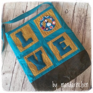 May include: A turquoise blue tote bag with a brown leather bottom. The bag is decorated with yellow squares with blue letters spelling out "LOVE" and a peace sign in the center. The bag has a long turquoise blue strap.