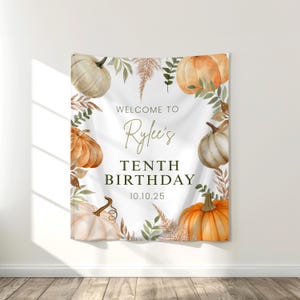 May include: A white banner with watercolor pumpkins and foliage. The banner reads "Welcome to Rylee's Tenth Birthday 10.10.25" in elegant script and block letters. The design features orange and cream pumpkins with green and brown leaves.