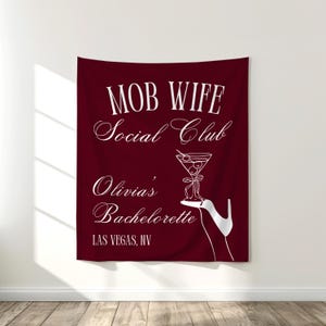 Peut inclure: Une tapisserie bordeaux avec du texte blanc et une illustration de cocktail. Le texte indique "MOB WIFE Social Club Olivia's Bachelorette LAS VEGAS, NV". L'illustration représente un verre à martini sur un talon haut.