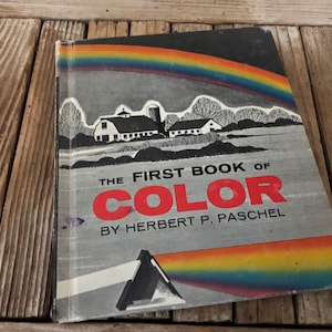 May include: The First Book of Color by Herbert P. Paschel, a vintage children's book with a black and white illustration of a farm and a rainbow on the cover.