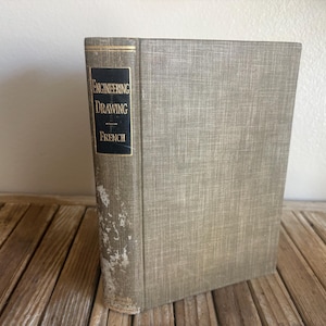 May include: A hardcover book titled Engineering Drawing by French with a textured light gray fabric cover. The spine features a black rectangular label with white text. The lower portion of the spine shows significant wear and material loss.