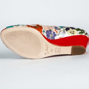 May include: The bottom of a floral print wedge heel shoe with a red sole. The shoe is a size 8 and is made of leather.