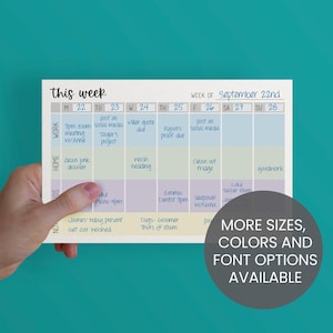 May include: A weekly planner with a teal background, held by a hand. The planner has a grid layout with the days of the week and space for notes. Text on the planner includes "this week" and "September 22nd". Additional text states "More sizes, colors and font options available."