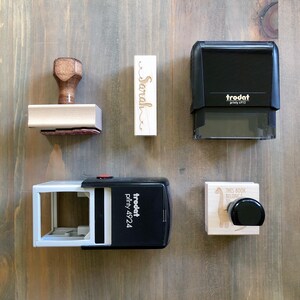 a collection of various items, including a wooden stamp, a black stamp, and a white stamp, arranged on a wooden surface.