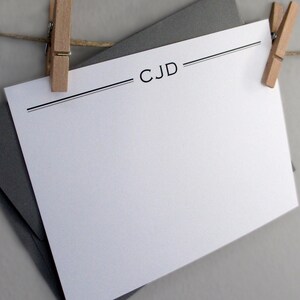 May include: A white card with black lines and the text "CJD" printed on it. The card is hanging from a string with wooden clothes pegs.
