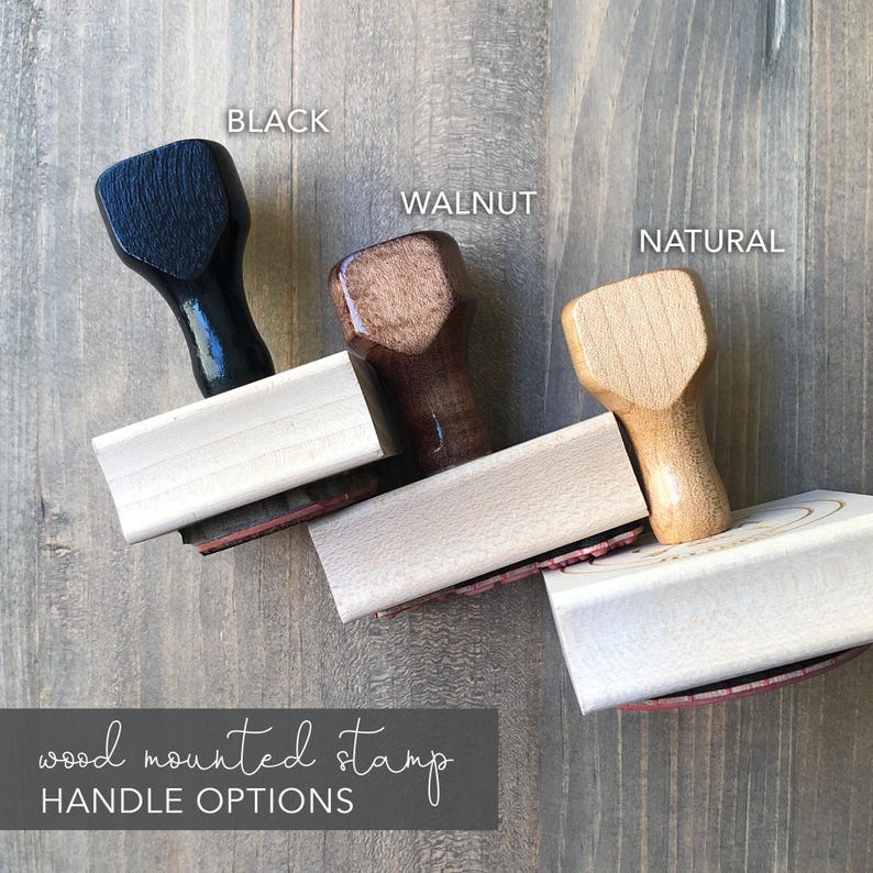 three different types of wood-mounted stamp handles, each with a distinct color and finish, arranged on a wooden surface.