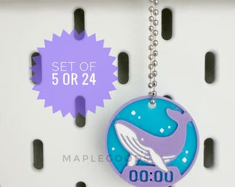 May include: A circular purple and blue keychain featuring a stylized whale graphic and the text 00:00. A purple starburst graphic displays the text SET OF 5 OR 24. The keychain includes a silver-toned metal ball chain for attachment.
