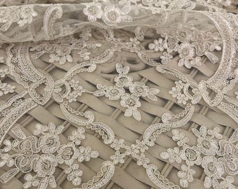 May include: White lace fabric with a delicate floral pattern. The lace is soft and sheer, with a subtle shimmer. It is perfect for adding a touch of elegance to any project.