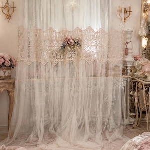 Può includere: Un pannello per tenda bianco e trasparente che arriva fino a terra, caratterizzato da un'ampia fascia orizzontale di pizzo beige lavorato al centro. Un piccolo mazzo di fiori artificiali rosa e crema è fissato sul pizzo.