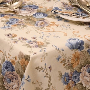 Könnte beinhalten: Eine cremefarbene Tischdecke mit einem floralen Muster mit blauen, braunen und gelben Blumen. Die Tischdecke hat einen dezenten Glanz und ein zartes Blumenmuster.