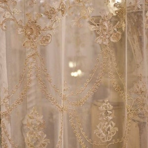 May include: A sheer white curtain with delicate gold embroidery featuring floral and vine patterns. The embroidery is intricate and adds a touch of elegance to the curtain.