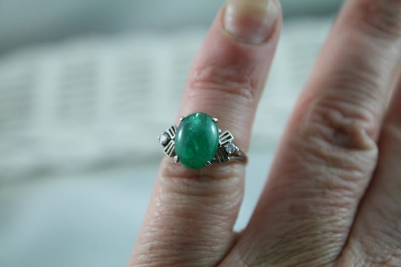 May include: A silver ring with a large oval emerald green gemstone and two smaller diamond accents.