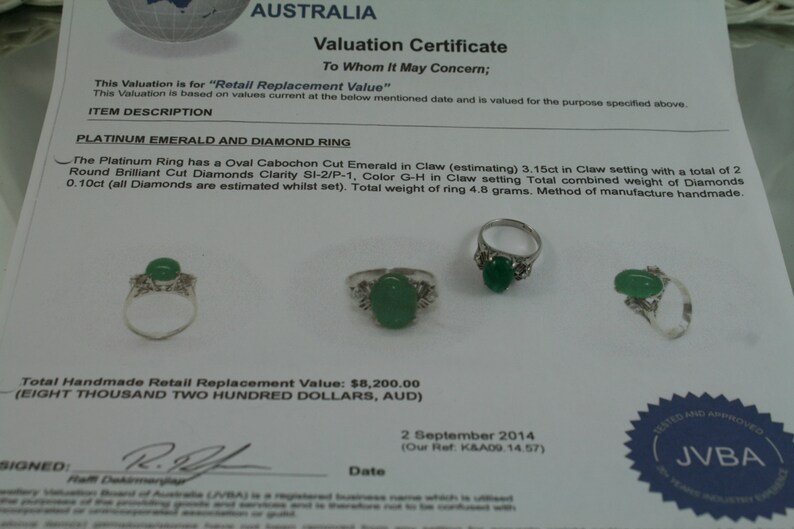 May include: A platinum emerald and diamond ring with a green oval cabochon cut emerald in a claw setting. The ring is surrounded by small round brilliant cut diamonds. The valuation certificate states the total weight of the ring is 4.8 grams and the total handmade retail replacement value is $8,200.00.