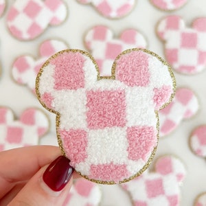 May include: Pink and white checkered Mickey Mouse shaped patch with a gold glitter outline.