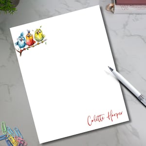 May include: White notepad with a watercolor illustration of three colorful birds perched on a branch. The birds are blue, orange, and yellow. The notepad has the name "Colette Harper" in red script.