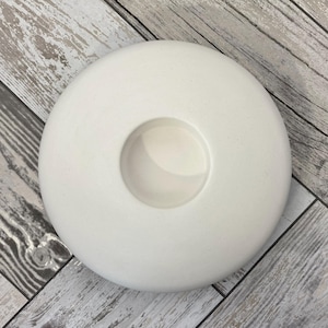 May include: White ceramic candle holder with a round base and a circular opening in the center.