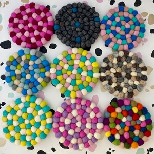 Può includere: Nove sottobicchieri rotondi in feltro colorati con una varietà di motivi. I sottobicchieri sono fatti di piccole sfere di feltro di diversi colori e motivi.