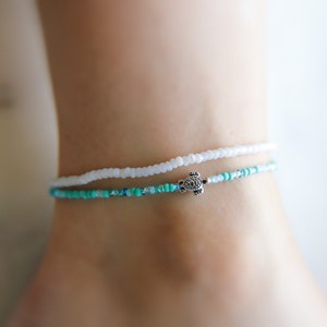 May include: A white and turquoise beaded anklet with a silver turtle charm.
