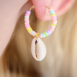 May include: A pair of hoop earrings with a pastel rainbow of beads and a white seashell charm.