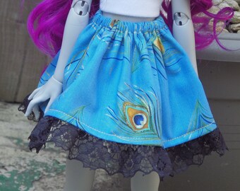 May include: A doll with purple hair wearing a white tank top and a blue skirt with a peacock design. The skirt has black lace trim.