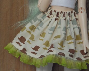 May include: A white skirt with a green lace trim and a brown and white pattern of mustaches and hats.