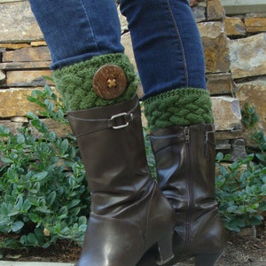 May include: Brown leather boots with green knitted leg warmers. The leg warmers have a large button on the front.