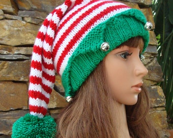 May include: A red and white striped elf hat with a green pom-pom and jingle bells. The hat has a long, pointed tip and a green brim.